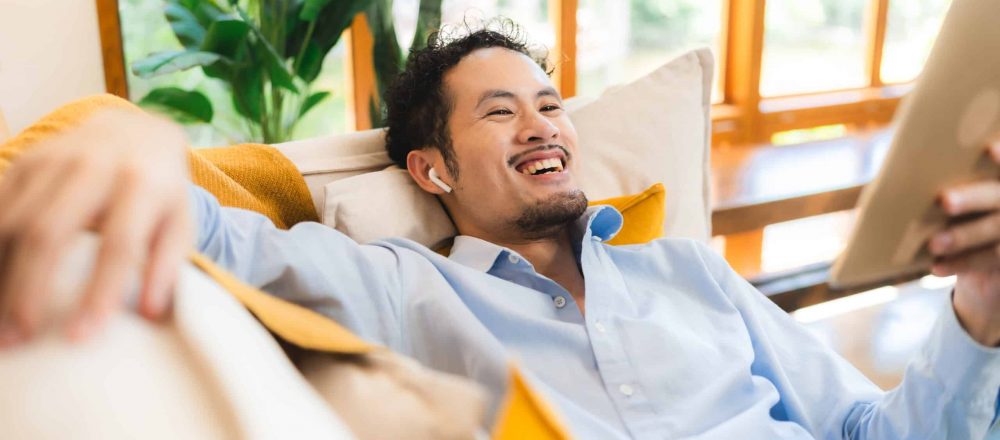 Entspannter Mensch mit Tablet auf Sofa.